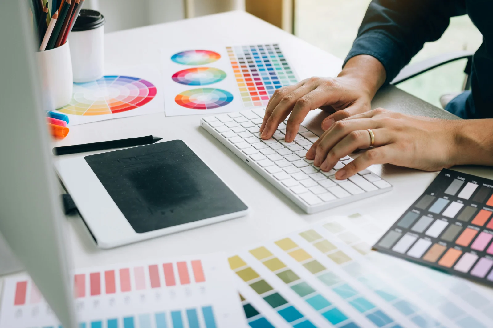 Employee working on brand compliance with a desk full of brand palettes