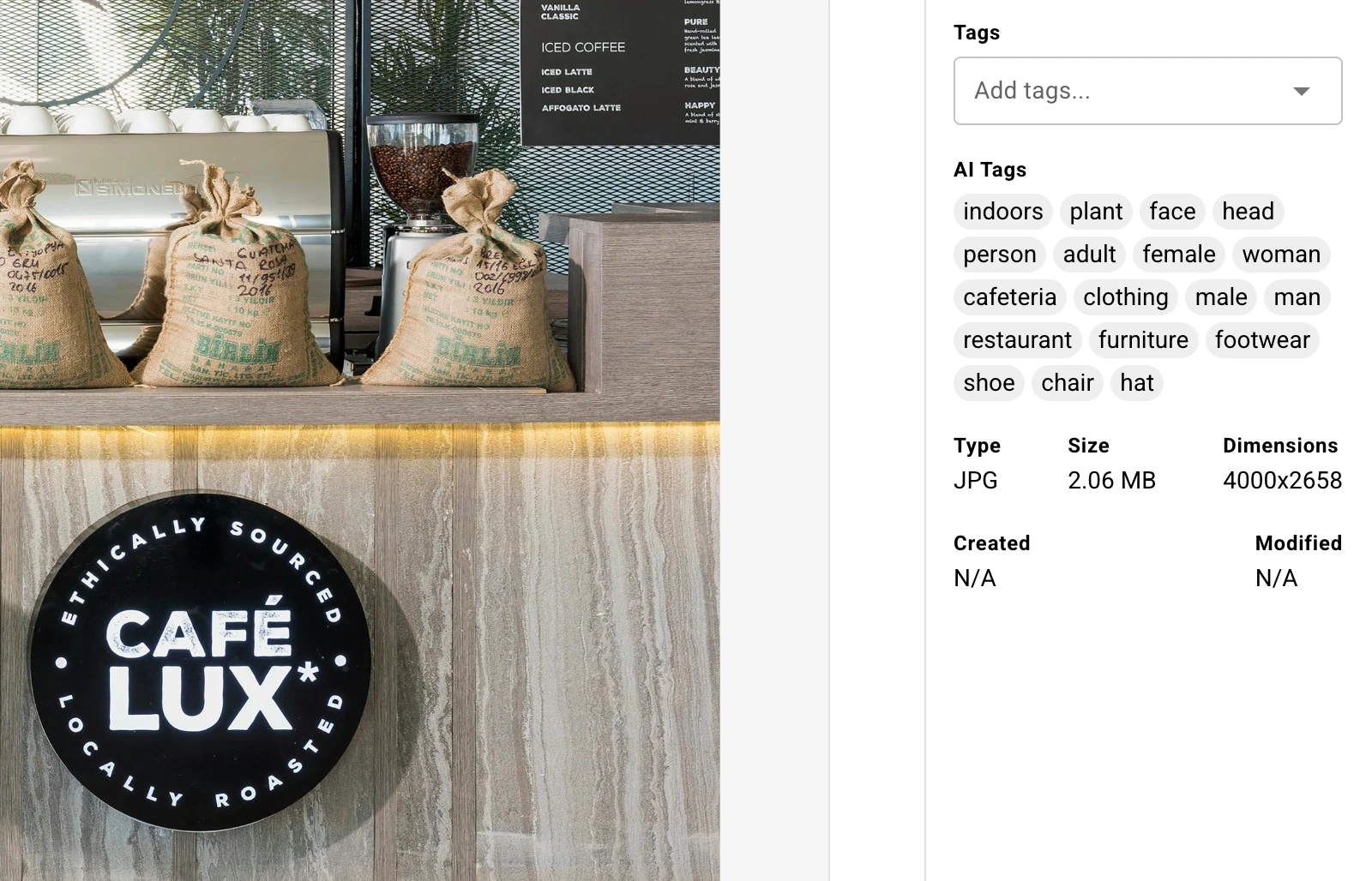 An asset detail panel in Baseline showing AI Tags generated from the image itself: indoors, plant, face, person, cafeteria, restaurant, furniture, footwear. None of these were typed by anyone.